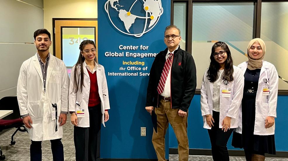 Four students and a doctor from Pakistan pose for a photo outside the Center for Global Engagement suite.