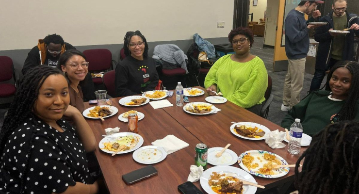 A group of students sit at a table with plates of food