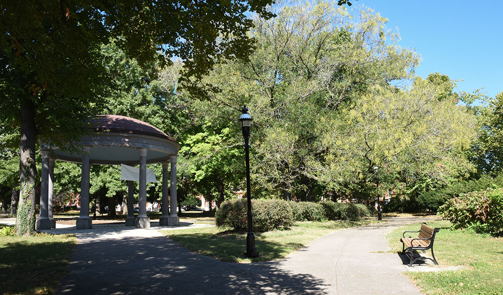 An arboreal park scene with a bench and gazebo