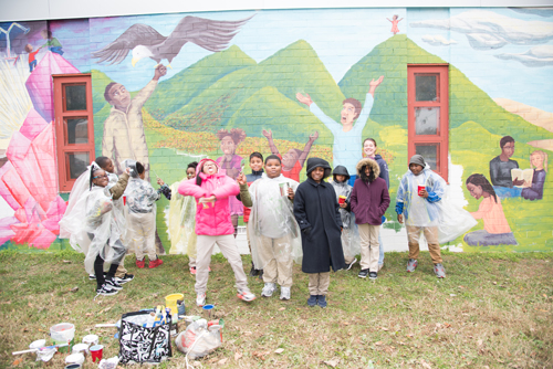Fourth-graders from James McHenry Elementary/Middle School help paint a mural on their school thanks to UMB's Council for the Arts & Culture, which sponsored the artwork. 