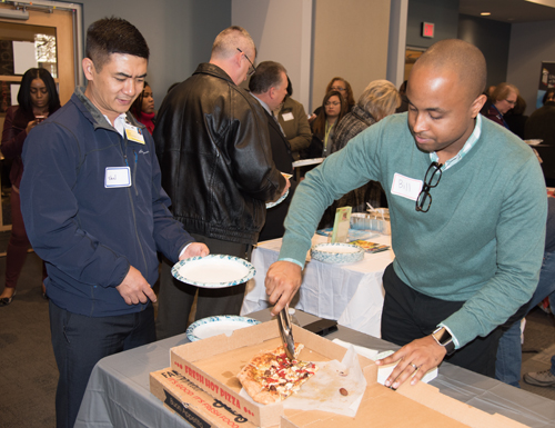 Bill Joyner, MSW, coordinator for UMB's Office of Community Engagement, serves Zella's pizza to Van Bik, a food and nutrition/sushi chef at University of Maryland Medical Center, at the Local Food Connection Fall Food Fair. 