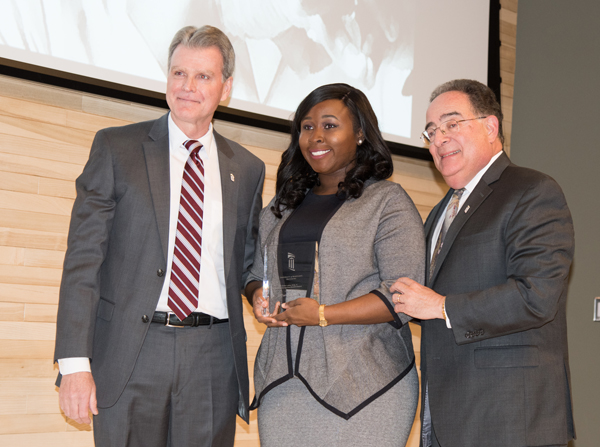 Tiffany C. Otto, a fourth-year dental student, received the Outstanding UMB Student Award for her work in the community and on campus furthering diversity. UM School of Dentistry Dean Mark A. Reynolds, DDS, PhD, left, assisted UMB President Jay A. Perman, MD, right, in the presentation.