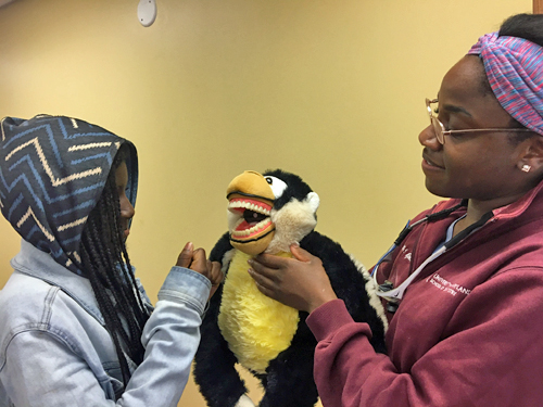 Using a puppet as a model, University of Maryland School of Dentistry student Ebbie Njoku teaches 10-year-old Taylor Sampson about flossing teeth at the University of Maryland, Baltimore's Second Annual Neighborhood Spring Festival on April 22.