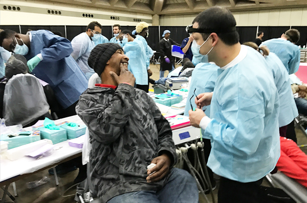 At a Mission of Mercy clinic during Project Homeless Connect, students from the University of Maryland School of Dentistry treat hundreds of patients, including Baltimore resident Ronald Ward, center, who describes his pain to Daniel DeCillis of the Class of 2018.