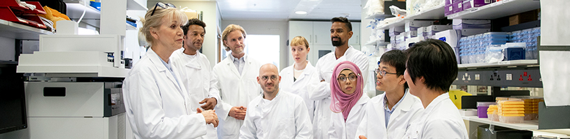 group of people discussing while wearing white coats in a lab