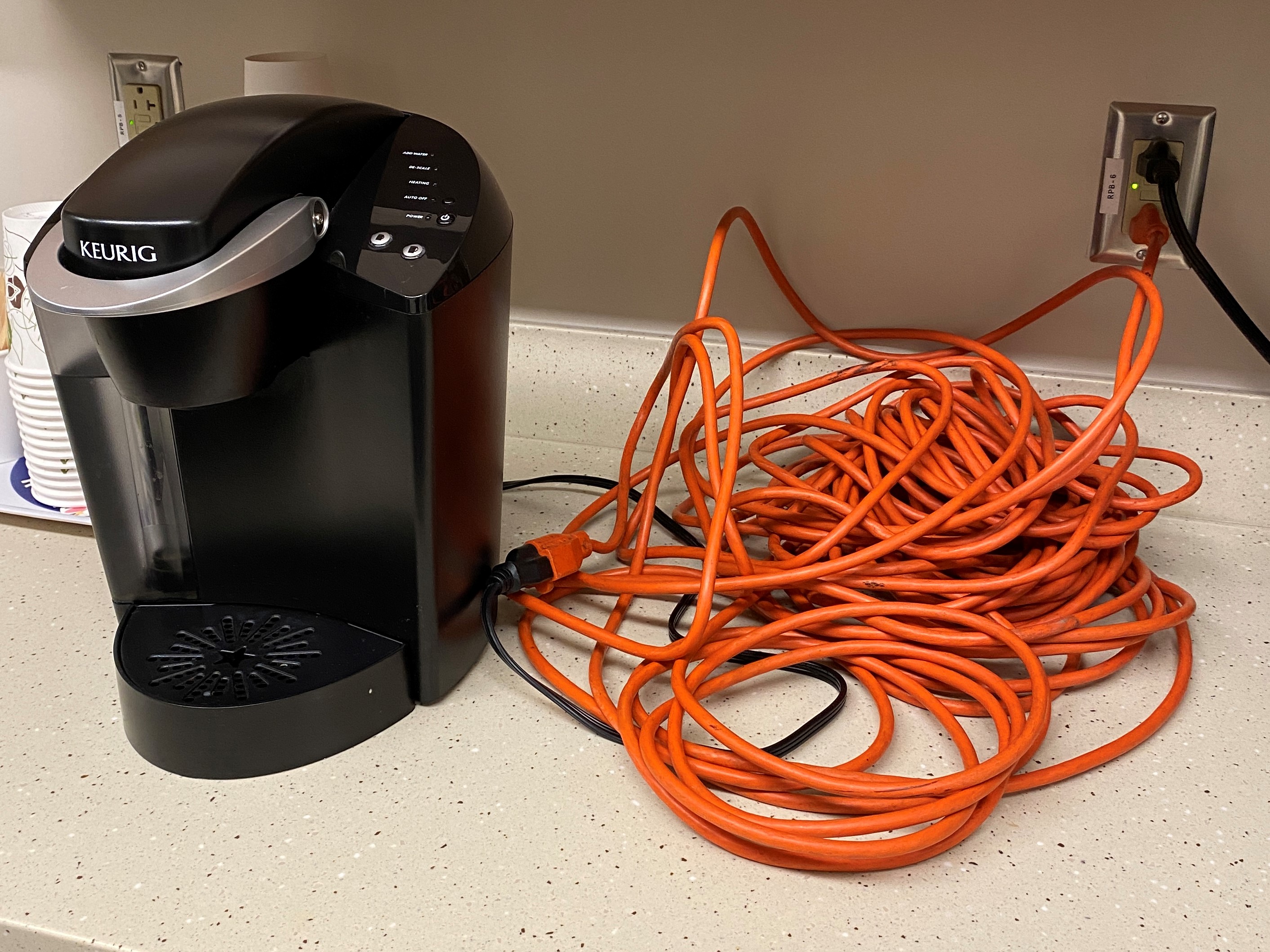 An extension cord connected to a coffee maker.