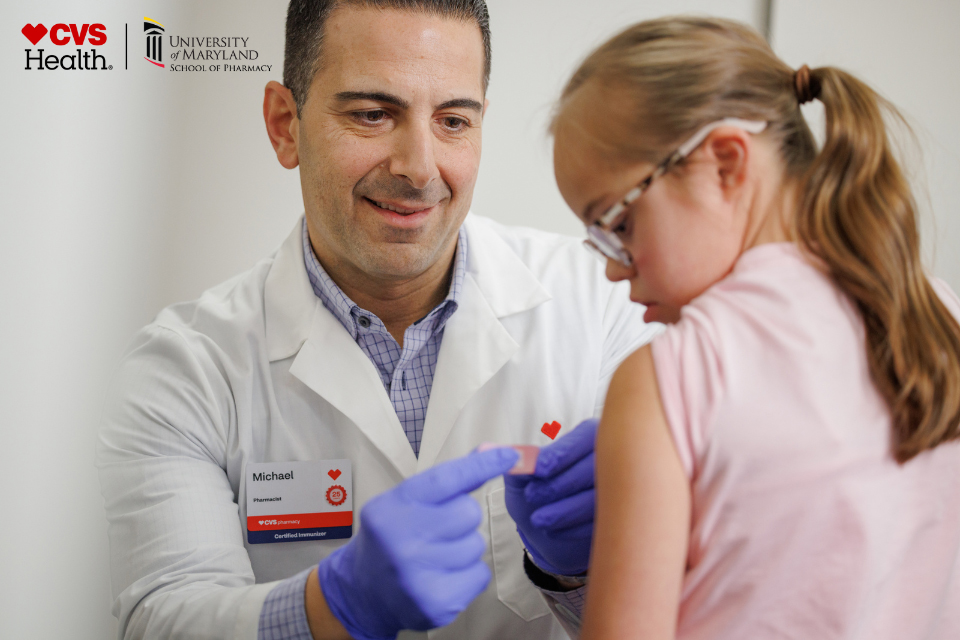 Pharmacist placing a bandage on a pediatric patient's arm