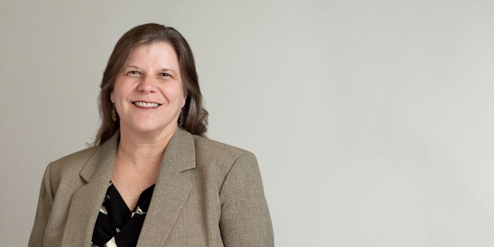 Elizabeth Galik, wearing a tan suit and black and white blouse