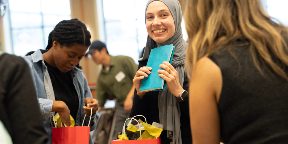 Students chat at the Global Kick Off and look through red gift bags.