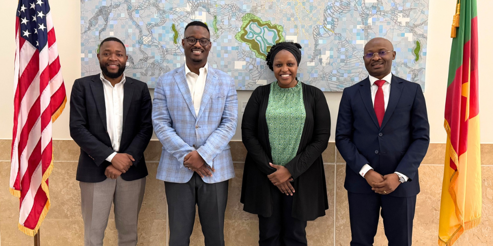 Abaneh Ebangwese poses for a photo with three men in front of a map.