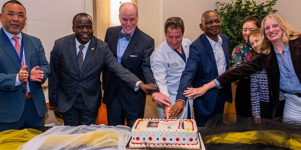 UMB and SOM faculty and staff cut a cake to celebrate the launch of the Global Health Alliance