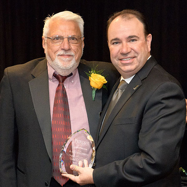 Gary Hollenbeck, left, receives an award from Purdue University