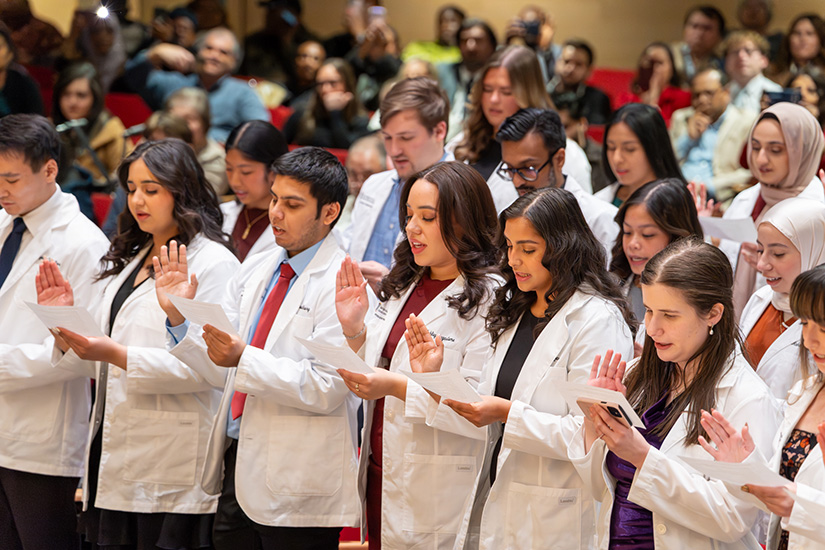 Physician assistant students take an oath after receiving their white coats