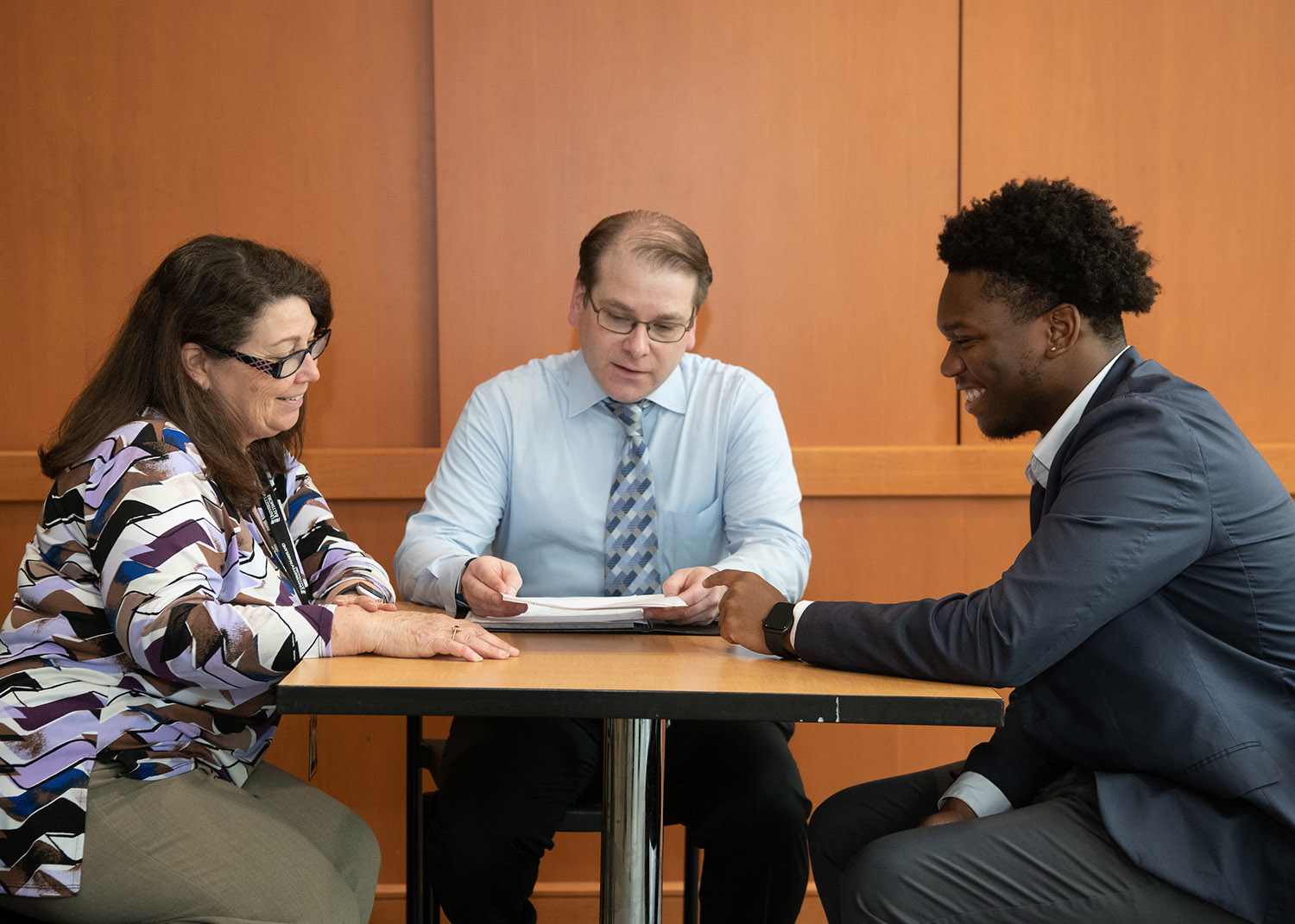 three professionals meet at a small table to collaborate