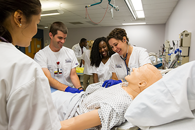 Nursing students surrounding a hospital bed