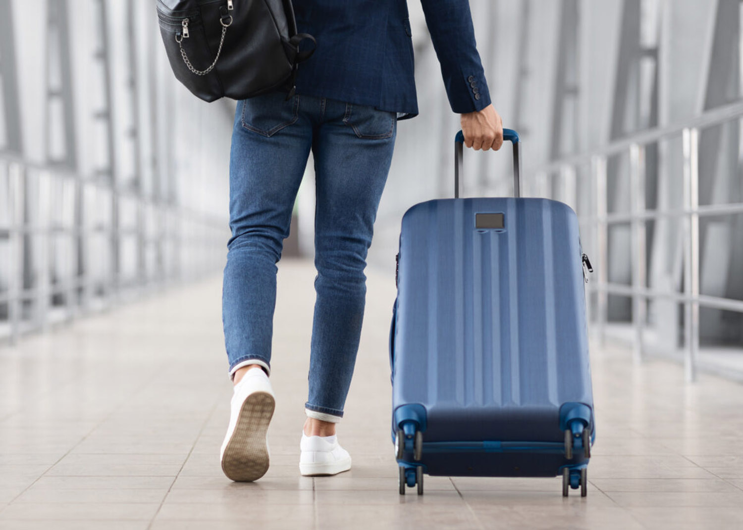 man with a backpack pulling a suitcase through an airport
