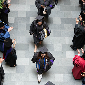 Graduates walking in a line through clapping faculty.