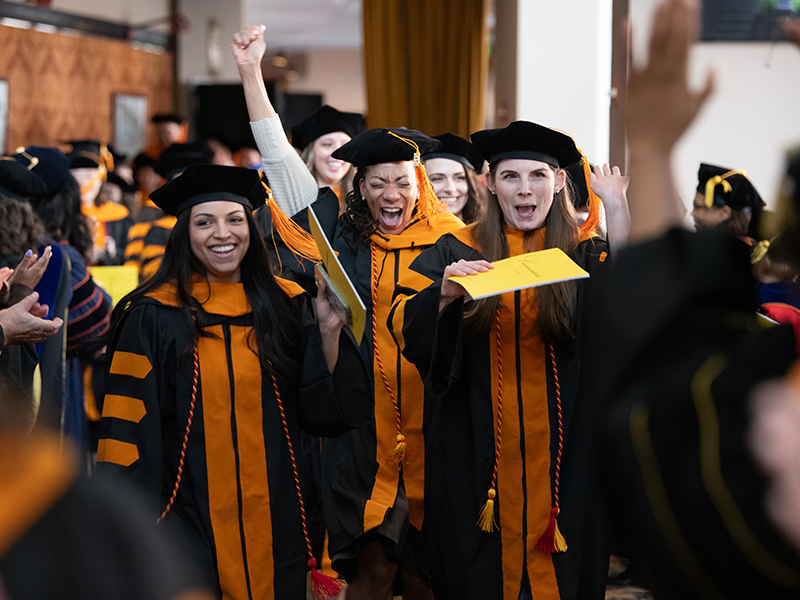 Group of SON students celebrating in their graduation garb.