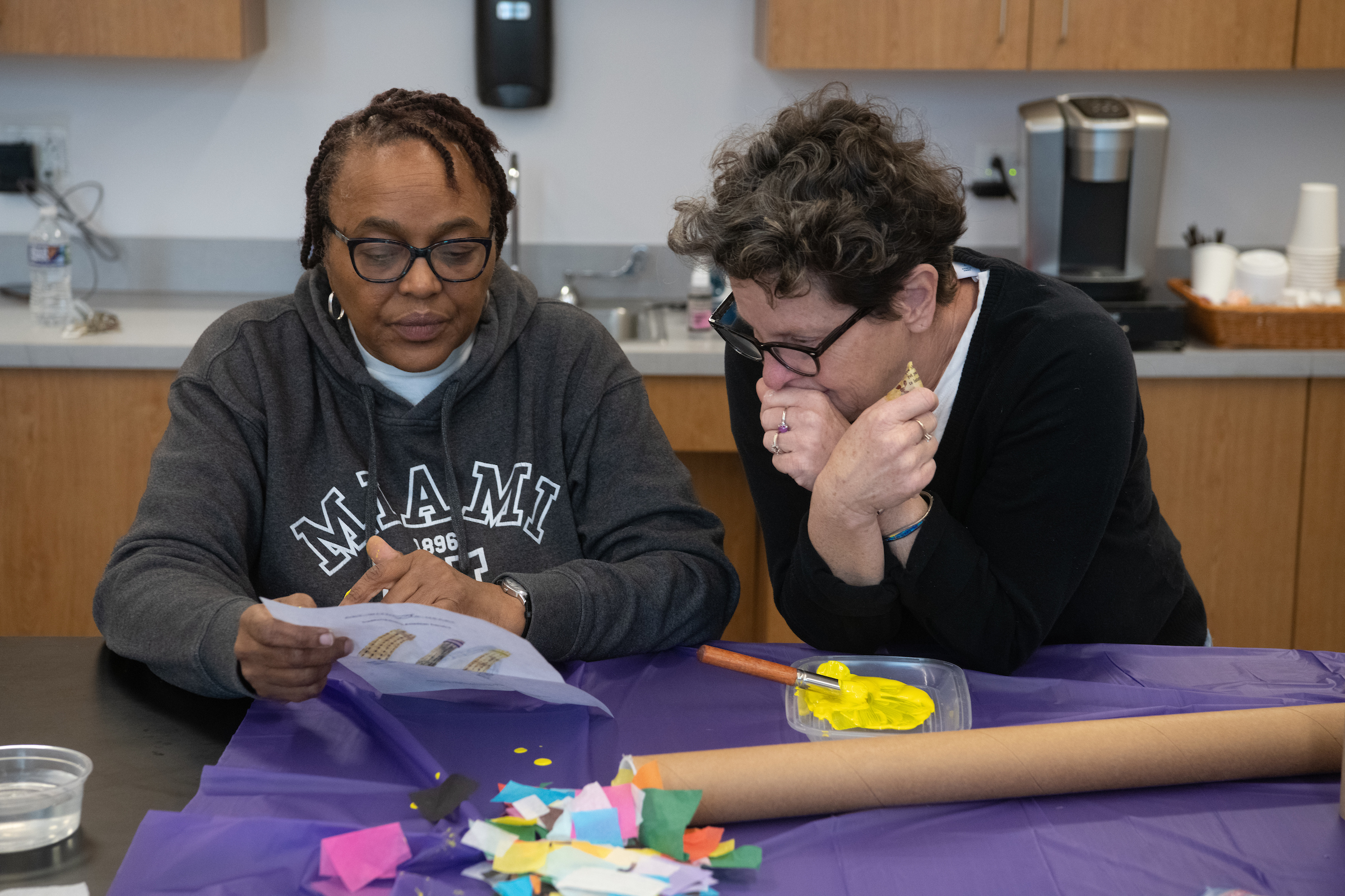 two adults working side by side on an art project