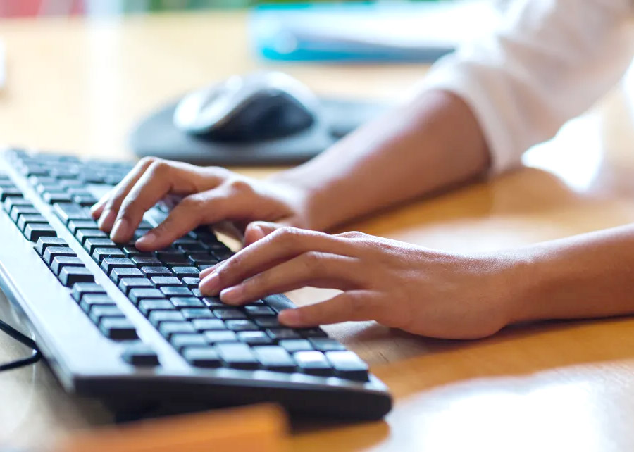 close up of hands typing on a computer keyboard