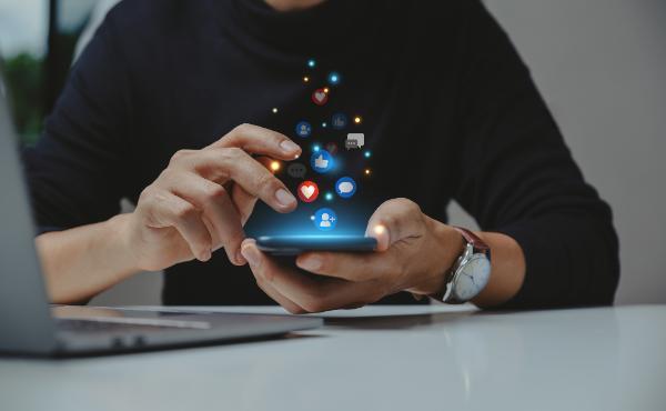 A person with a phone with icons coming out of it. 