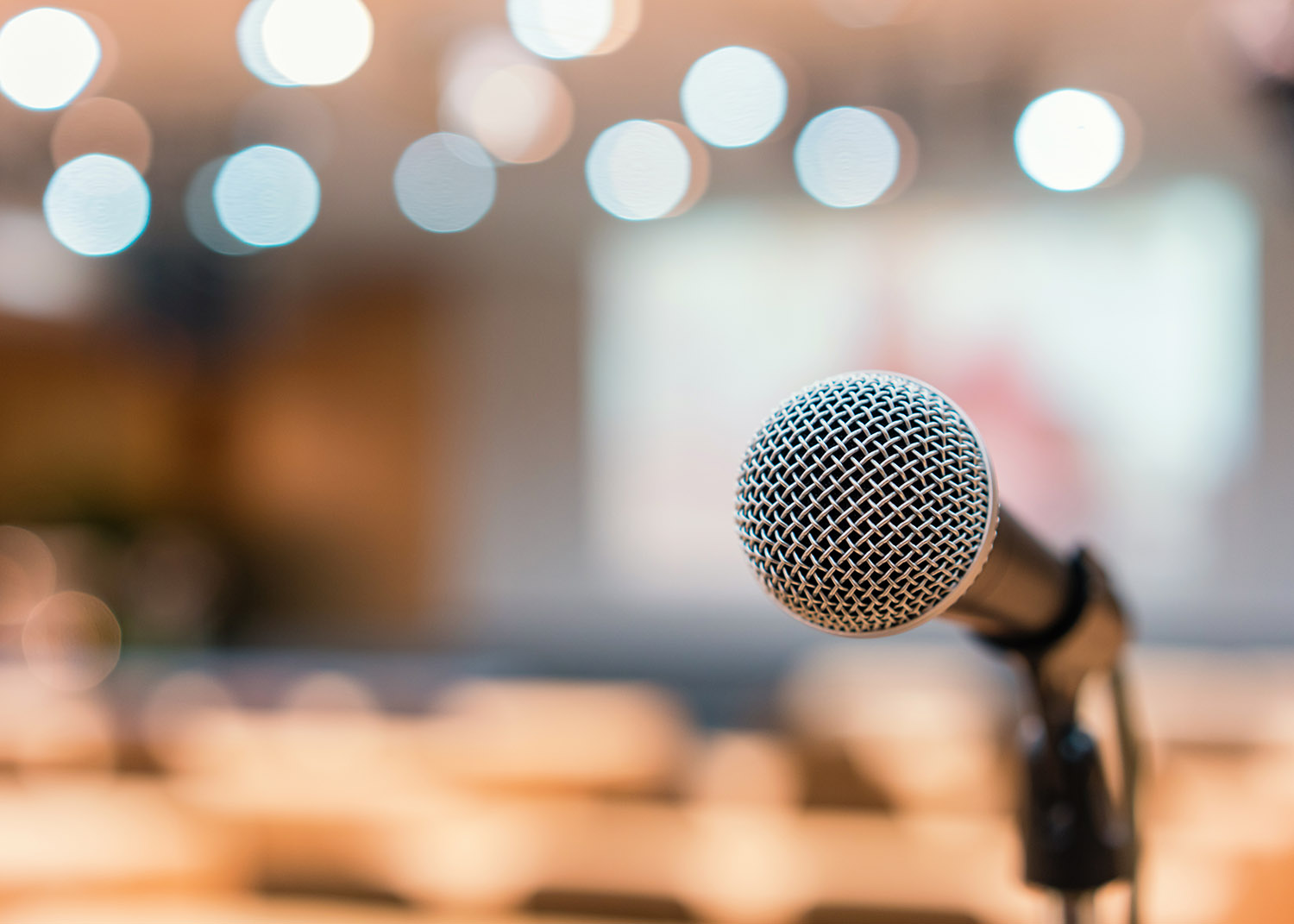 microphone in forefront, chairs in a meeting hall in the background