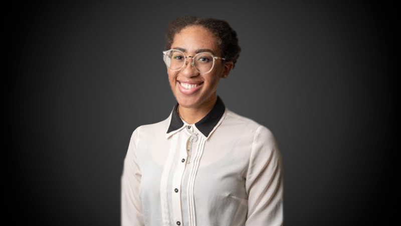 Portrait of a professional student in a tan collared shirt on a dark black and gray gradient background