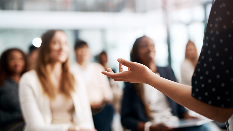 Photo of a group of diverse women sitting down listening to a speaker 