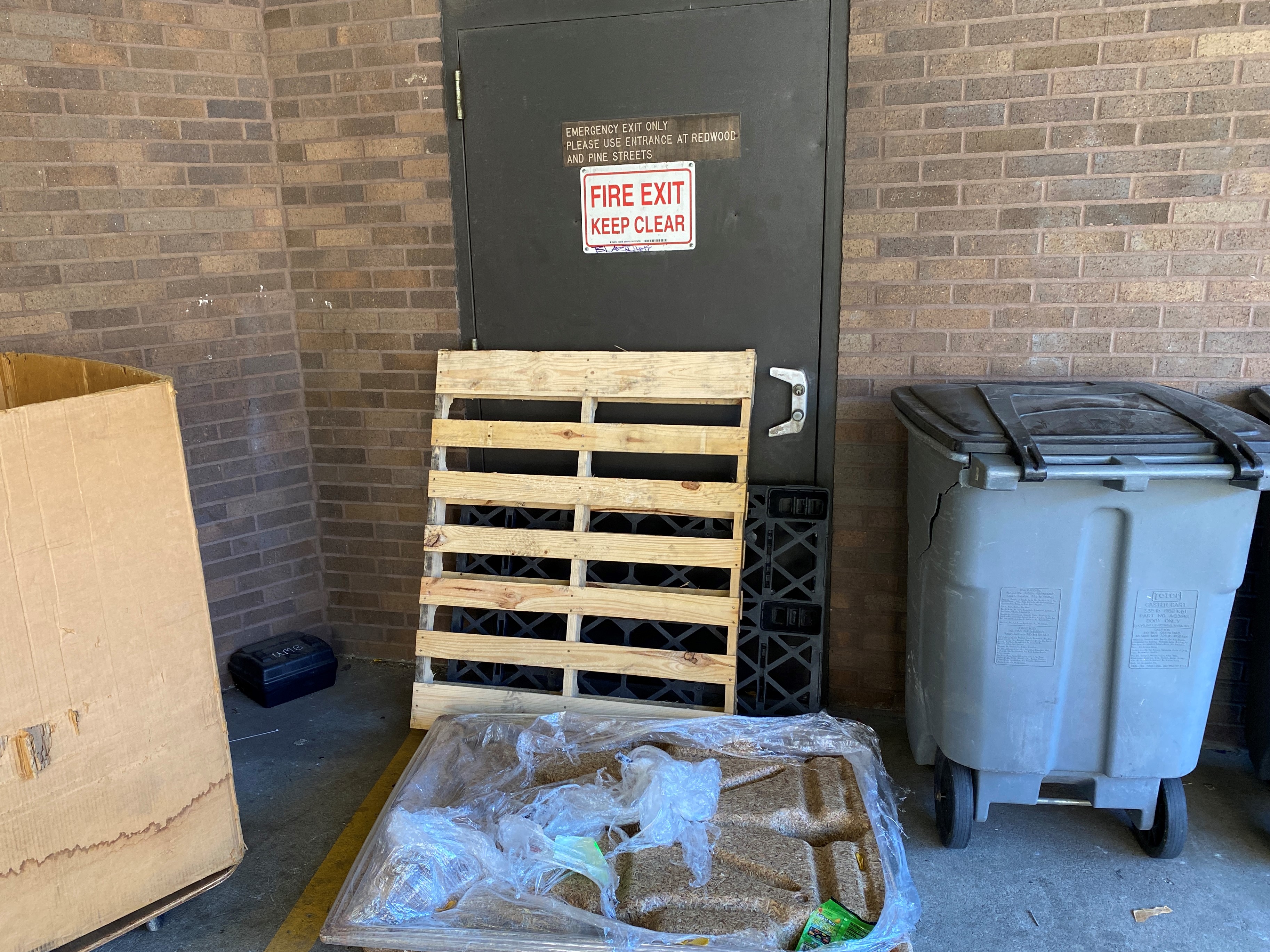 An exit door obstructed with pallets and trash.
