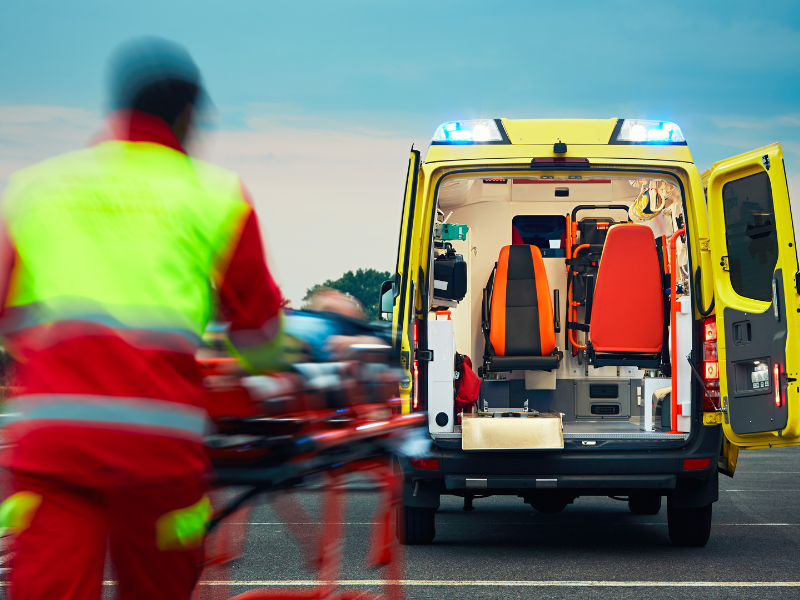 A paramedic rushes a gurney towards an open ambulance