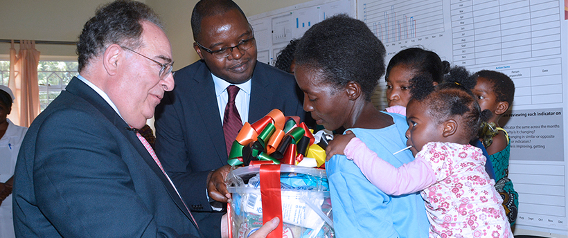 President Perman giving an item to a mother and her children