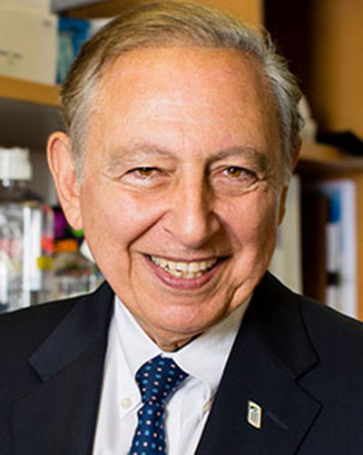 Man in suit and tie with bookcase behind him