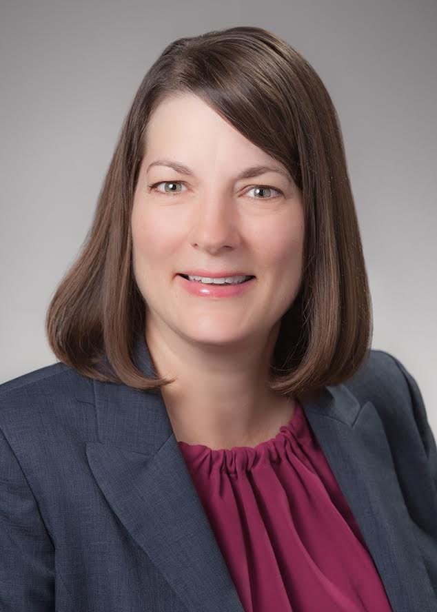 Headshot of woman wearing a grey suit and maroon shirt