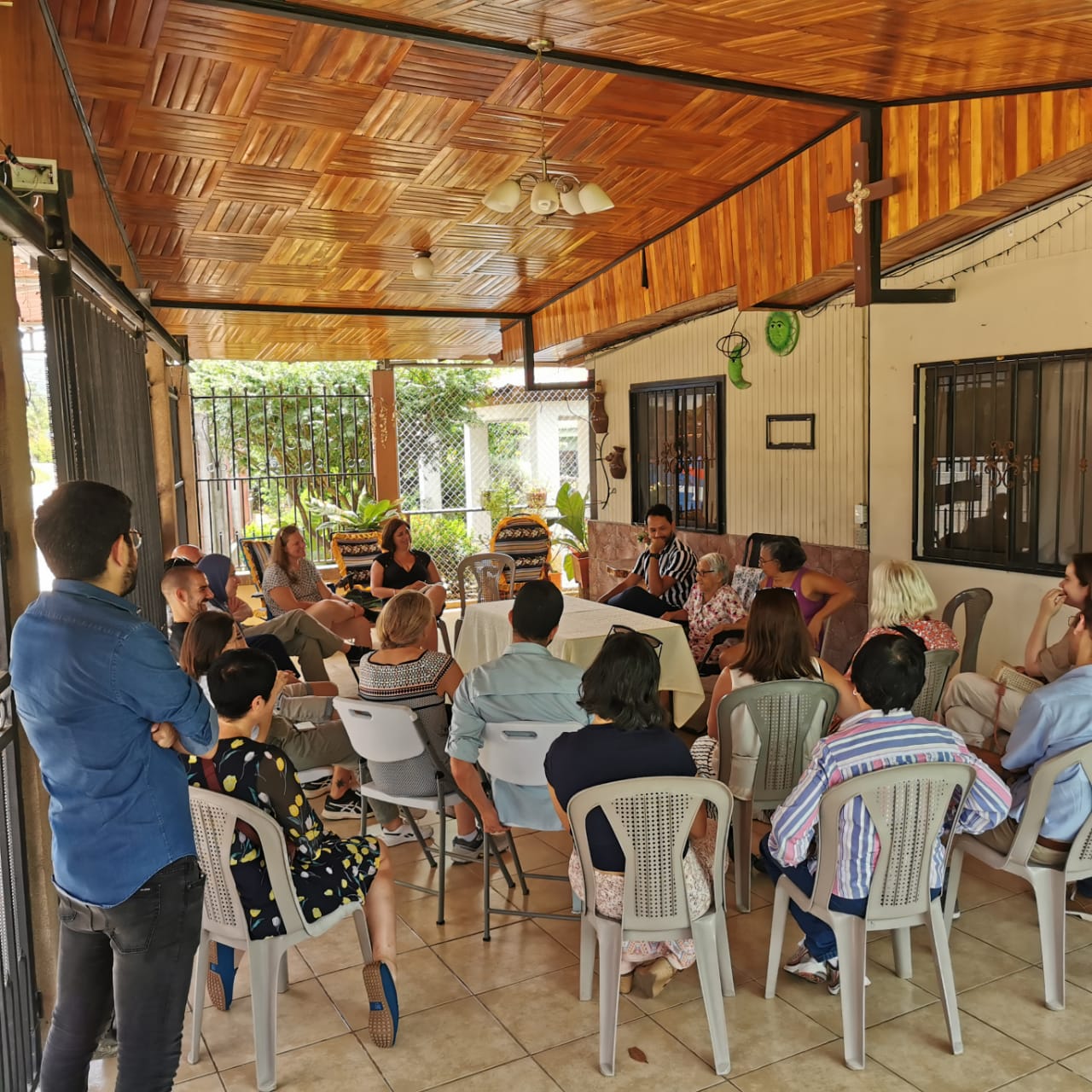 A group of people sit in chairs around a centenarian, who's speaking