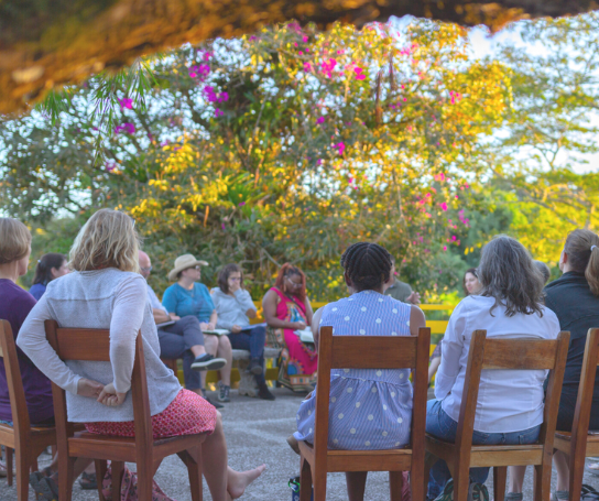 A group of people sit in a circle outside