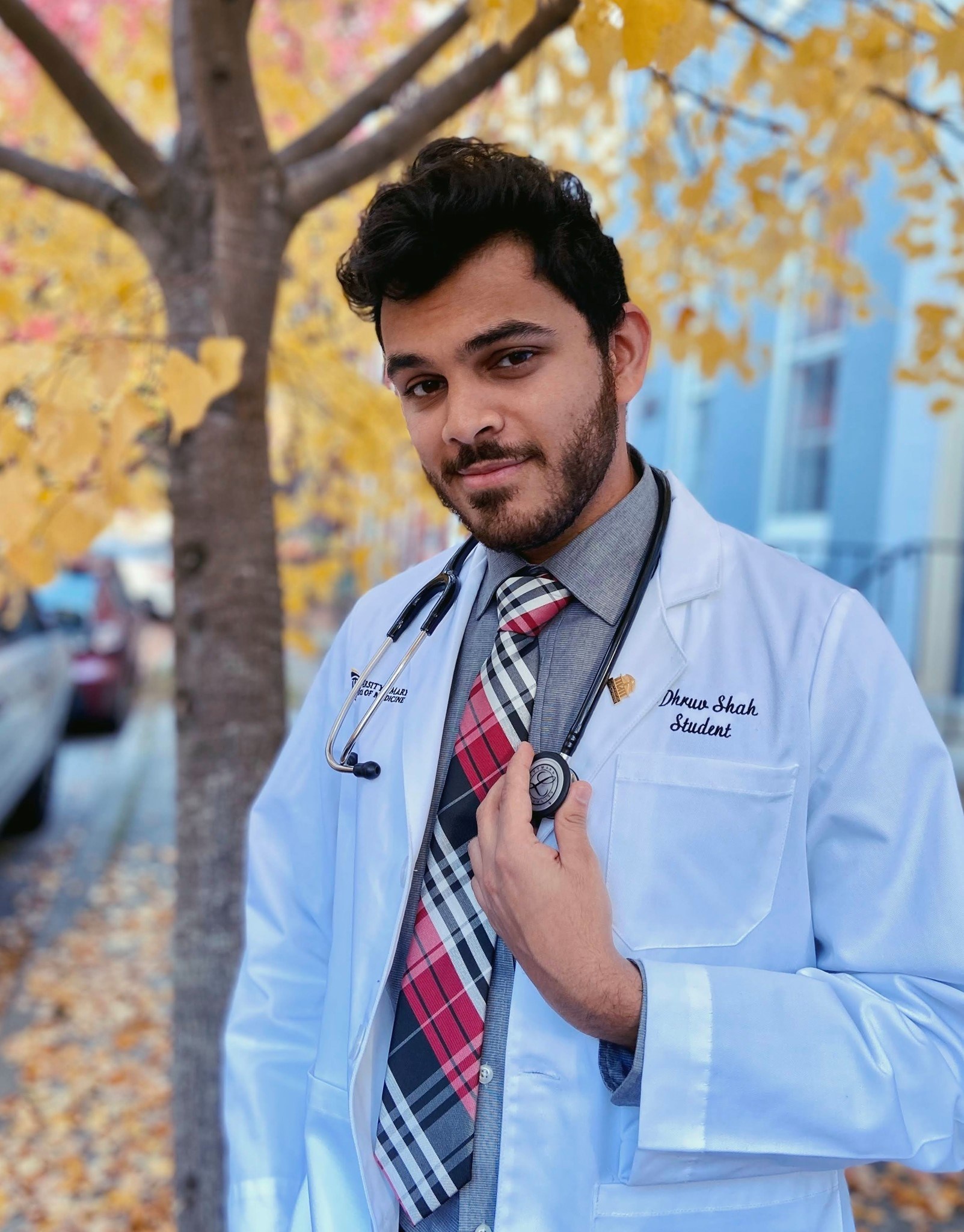 Photo of student wearing a medical jacket with a tree in the background