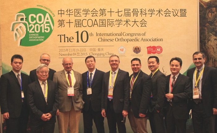 Ten men in suits stand in a line in front of large banner for the International Congress of Chinese Orthopaedic Association 