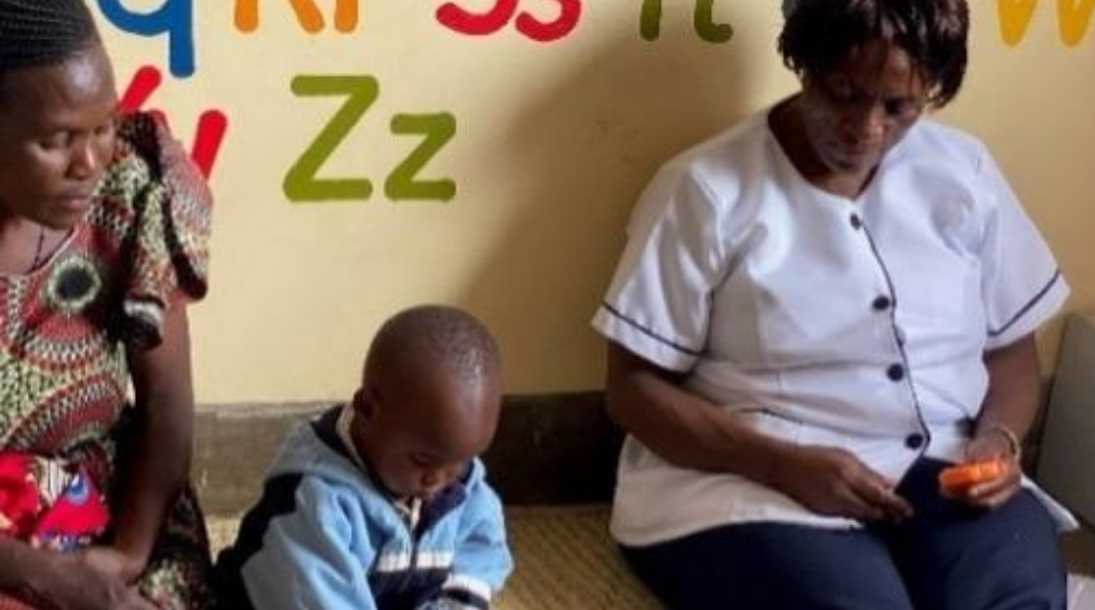 Two women watch a child play