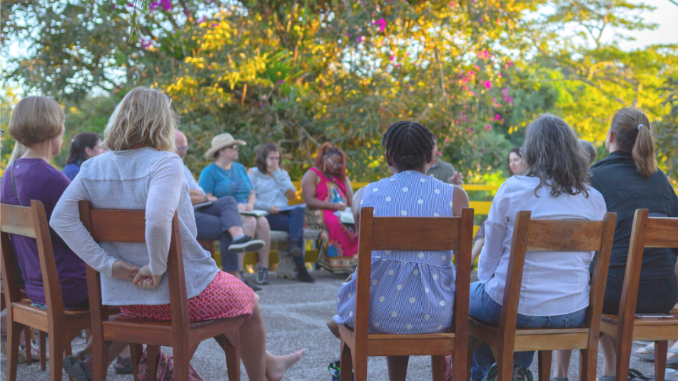 A group of people sit in a circle outside