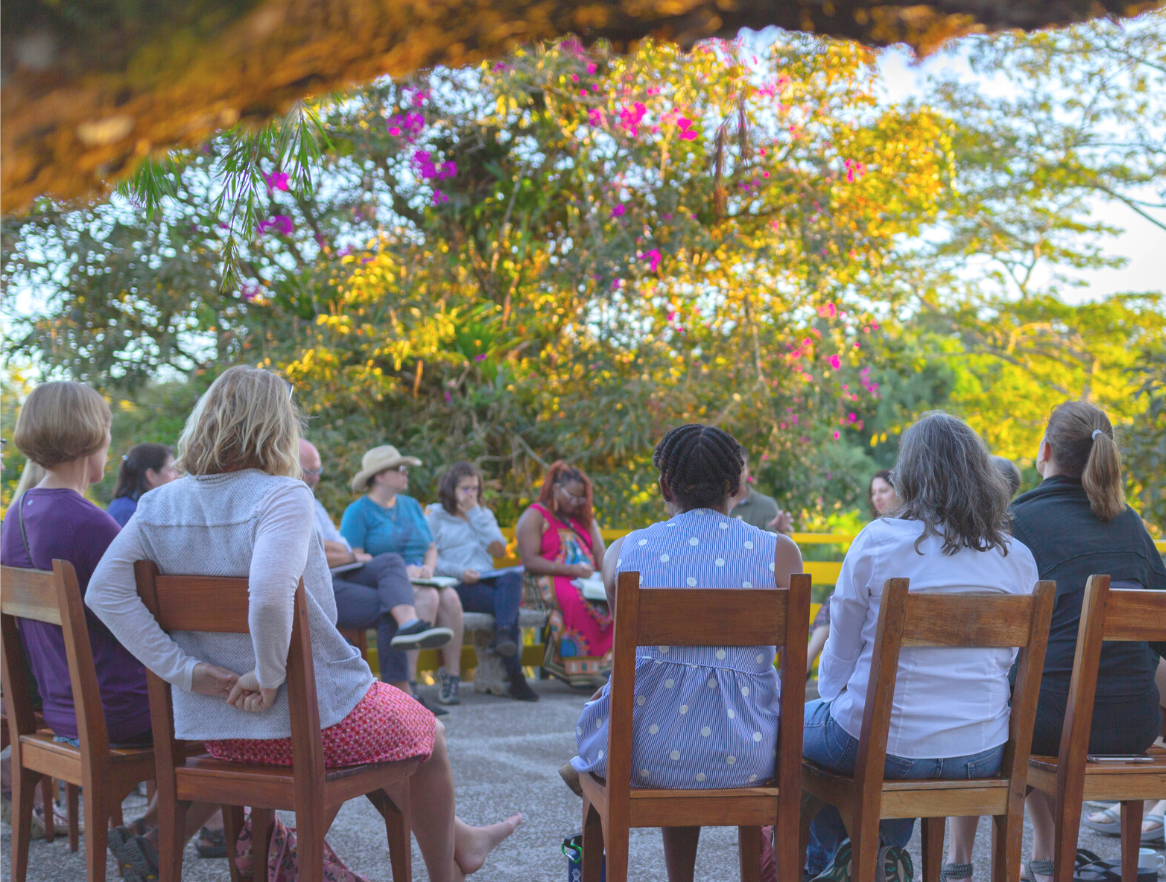 A group of people sit in a circle outside