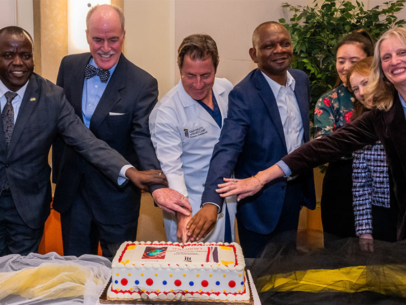 UMB and SOM faculty and staff cut a cake to celebrate the launch of the Global Health Alliance.