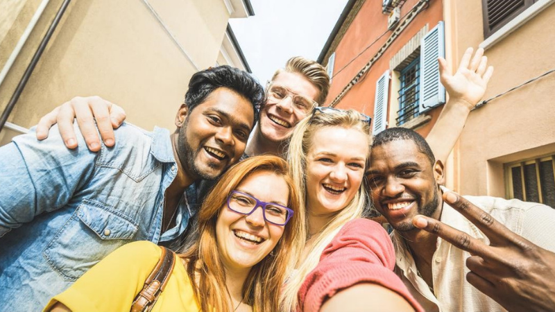 Group of two men and three women of diverse races gather in group for selfie
