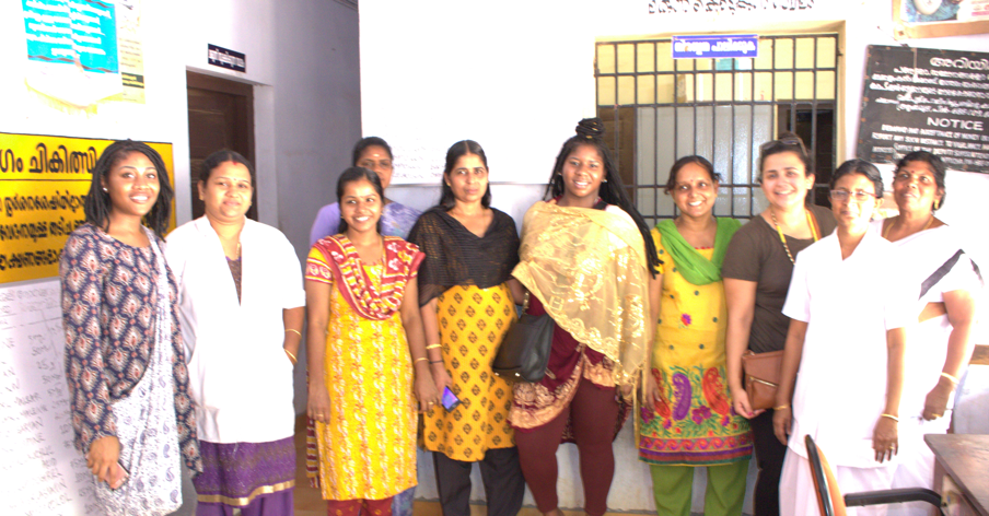 Women stand in a line for a photo, many wearing saris.
