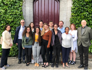 Students and professors gather for a group shot in front of an ivy-covered building