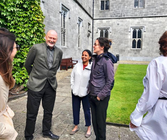 A group of students and faculty chat outside a building in Ireland