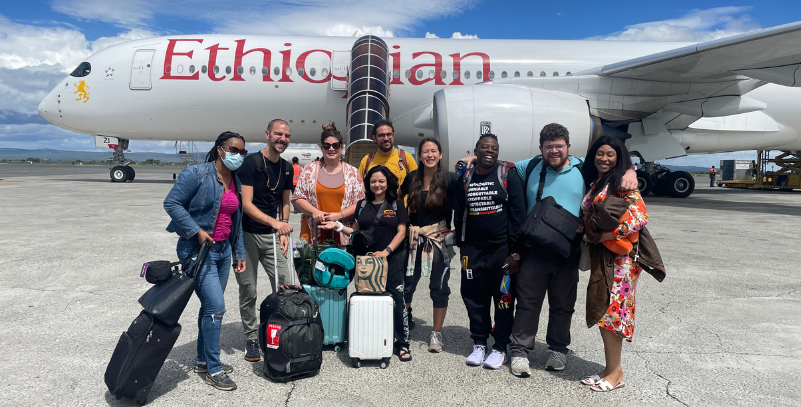 A group of UMB students and faculty pose beside an Ethiopian Airlines plane