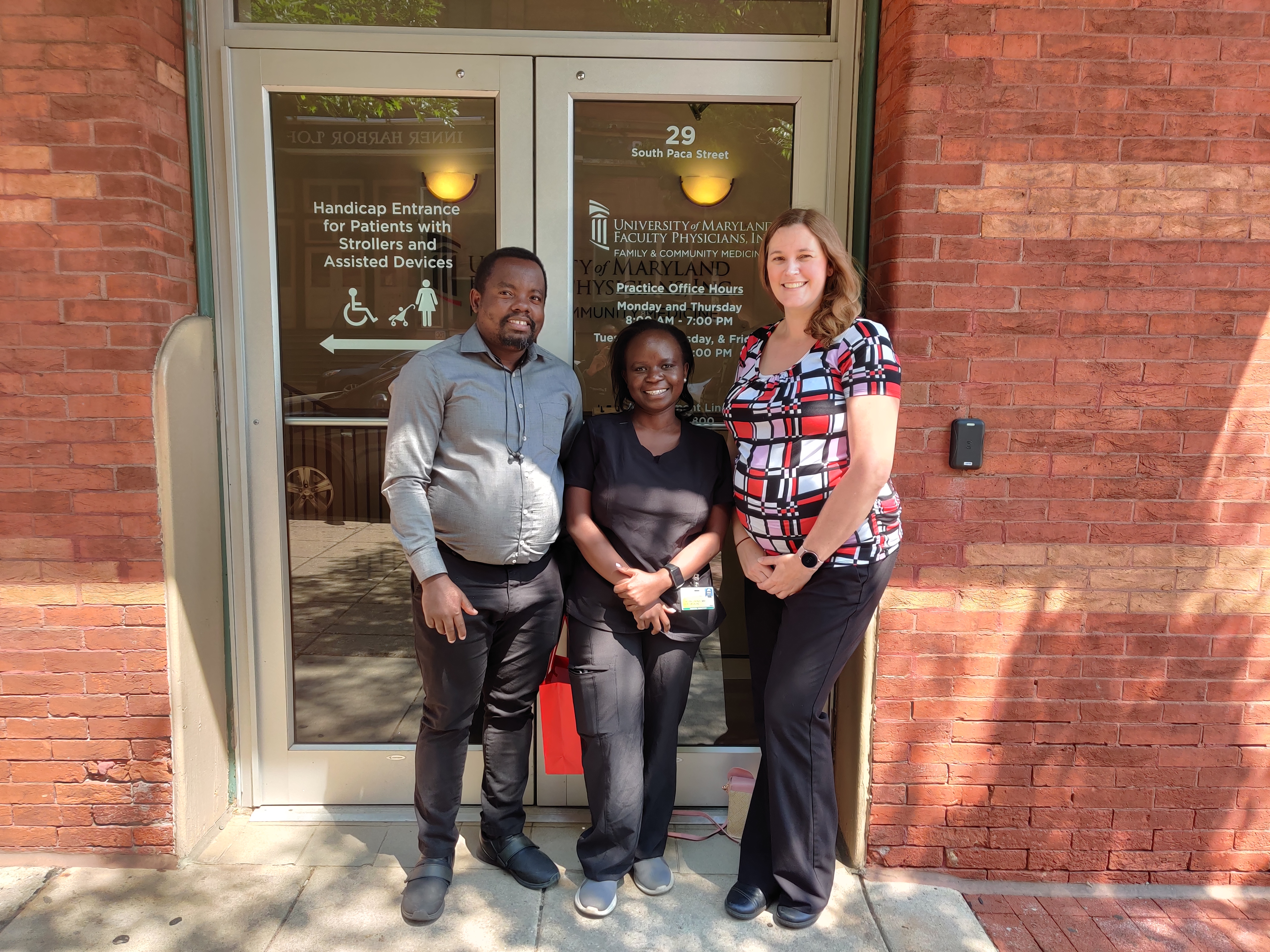 Three people stand outside door to a building