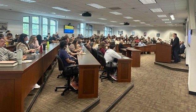 Law students from UMB and Malawi sit at desks listening to a professor speak at a podium