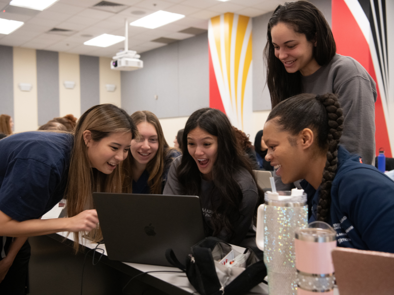 Students work together at a laptop