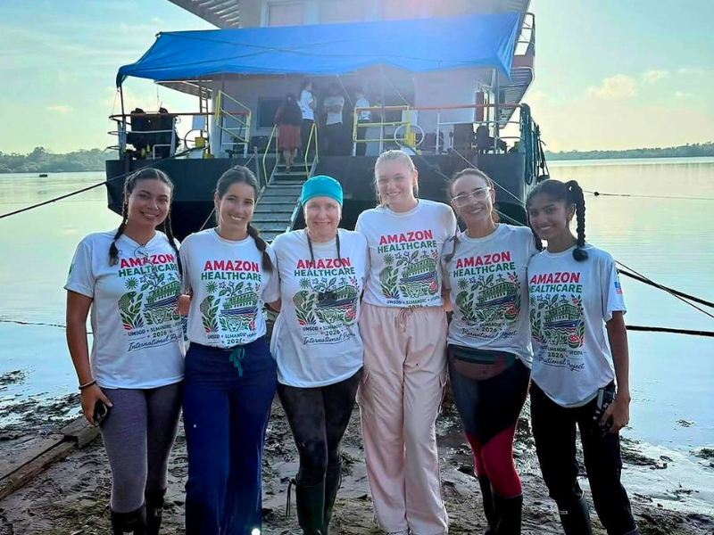 Students and faculty pose beside a boat in the Amazon